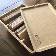 an open cardboard box filled with books on top of a wooden table