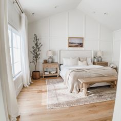 a bedroom with white walls and wood floors