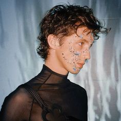 a woman with glitter on her face standing in front of a wall wearing a black top