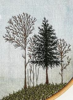 a cross stitched picture with trees and grass in the foreground, on a white background