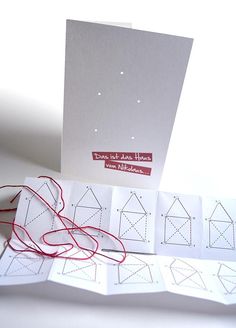 four cards with red string attached to them on top of a white table next to some scissors