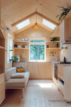 a living room and kitchen area in a small cabin style home with wood flooring