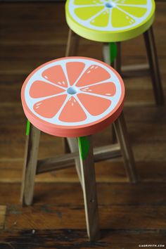 two small stools with orange slices painted on them sitting on a wooden floor next to each other