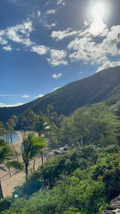 the sun shines brightly on a tropical beach with palm trees and mountains in the background