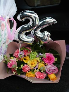 a bouquet of flowers and balloons in the back of a car