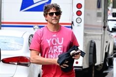 a man in a pink shirt and sunglasses walking down the street with an open wallet