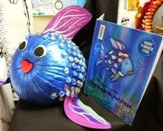 a blue fish statue sitting next to a book on a black table with other items