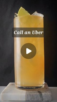 a tall glass filled with lemonade sitting on top of a marble block next to a black background