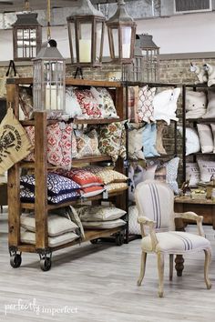 a room filled with lots of furniture and pillows on display in front of a brick wall