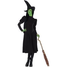 a woman in a witches costume holding a broom and wearing a black hat with green eyes