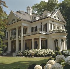 a large white house surrounded by trees and flowers