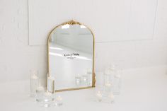 a mirror sitting on top of a white table next to many lit candles in front of it