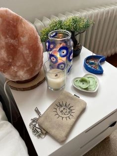 an assortment of items sitting on a table next to a candle and glass vases