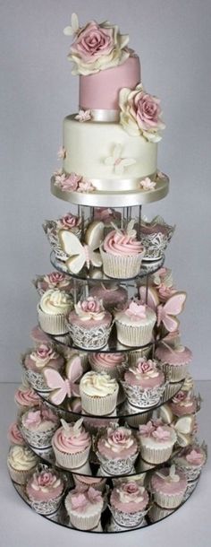 a three tiered cake with cupcakes on the bottom and pink roses on top