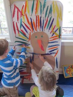 two young children are painting a turkey on a bulletin board with crayon pencils