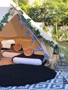 a tent set up in the middle of a yard with black and white rugs