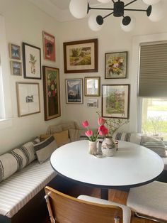 a white table and some chairs in a room with pictures on the wall above it