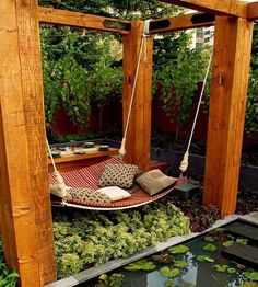 a hammock hanging in the middle of a garden with lily pads and water lilies