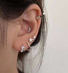 a woman's ear with three stars attached to the back of her piercings