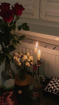 roses in vases and wine bottles are sitting on a table with a chess board