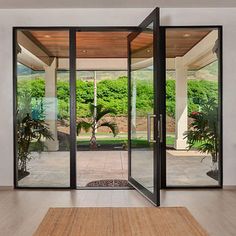 an open glass door leading to a patio with potted plants on the side walk