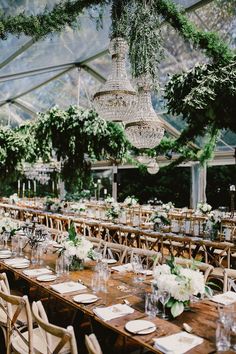 a long table is set with place settings and greenery for an outdoor wedding reception