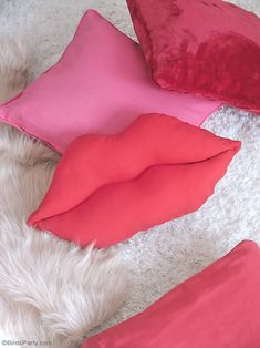 four pillows are laying on the floor next to each other, one is pink and one is red