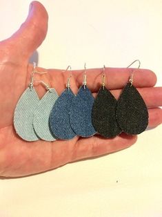 a hand holding four pairs of leather earrings