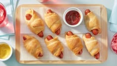 hotdogs wrapped in bread with ketchup and mustard on a cutting board