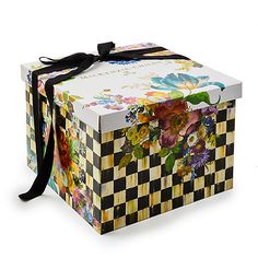 an open box with flowers painted on the side and black ribbon tied around the top