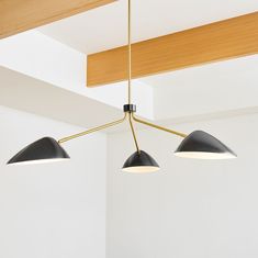 three lights are hanging from the ceiling in a room with white walls and wood beams