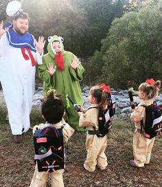 a group of children standing next to each other wearing costumes and holding hands in the air