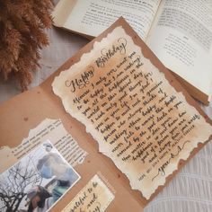 an open book with writing on it next to two pictures and a pine tree in the background