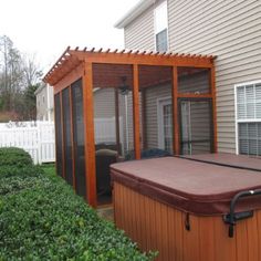 a hot tub sitting in the middle of a yard next to a house and bushes