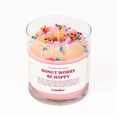 a candle that has sprinkles on it in a clear glass container with the words don't worry be happy