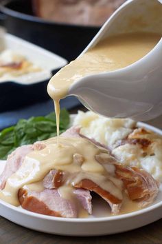 someone pouring gravy on top of mashed potatoes with ham and gravy