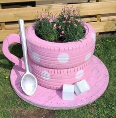 a pink potted planter made out of old tires with flowers growing in it