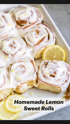 a pan filled with lemon rolls covered in icing and topped with sliced lemons