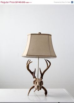 a lamp that is sitting on top of a table with a deer's head underneath it