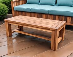 a wooden bench sitting on top of a hard wood floor next to a blue couch