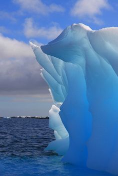 an iceberg floating in the ocean on a sunny day