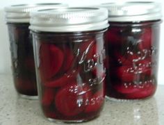 three jars filled with pickles sitting on top of a counter