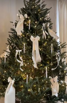 a christmas tree decorated with white ribbons and lights