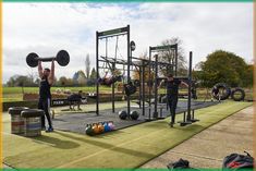 a group of people working out with barbells and weight machines in a park