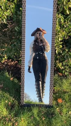 a woman taking a selfie in front of a mirror with her hat and boots