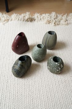 five small vases sitting on top of a rug