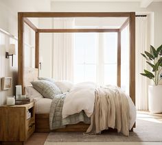 a bed with white sheets and pillows in a bedroom next to a plant on a dresser