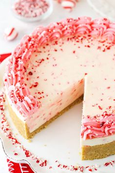 a white cake with pink and red sprinkles sitting on top of a plate