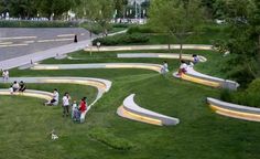 several people are standing on the grass in front of an outdoor area with stairs and lights