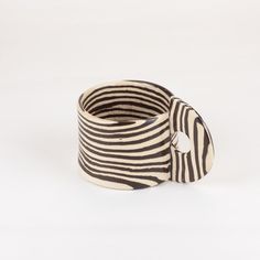 a black and white striped bracelet with a button on it's end, sitting in front of a white background